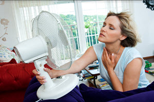 woman cooling herself with a table fan