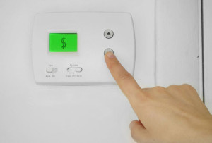 woman turning down a thermostat